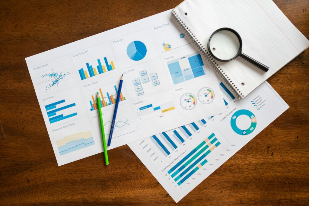 pexels-photo-7947846-7947846 Overhead view of financial charts, magnifying glass, and stationery on wooden table.