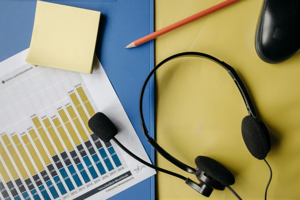 A flat lay image depicting an office desk with a headset, chart, and stationery for business use.